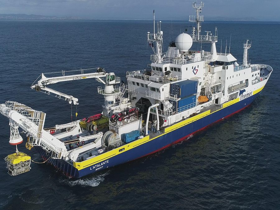A research ship craning a robot
